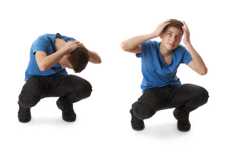 Cute teenager boy in blue T-shirt sitting and closing head with hands over white isolated background full bodyの写真素材