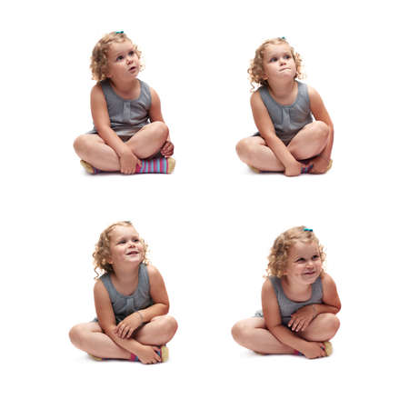 Young little girl with curly hair in gray dress sitting over isolated white backgroundの写真素材