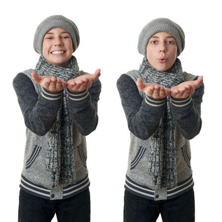 Set of cute teenager boy in gray sweater, hat and scarf holding something over white isolated background, half bodyの写真素材