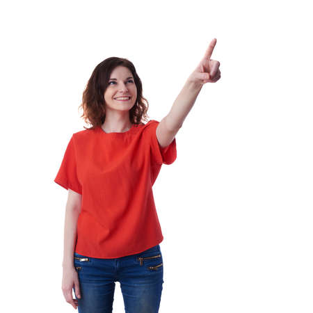 Smiling young woman in casual clothes over white isolated background pointing, showing direction or pushing button, happy people conceptの写真素材