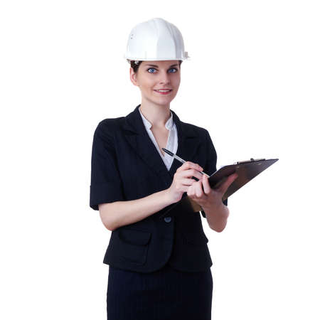 Smiling businesswoman standing over white isolated background in white helmet with clipboard, business, education, construction and architecture conceptの写真素材