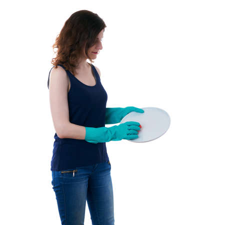 Smiling young woman in dark T-shirt and green rubber gloves over white isolated background washing ceramic plate, cleaning and healthy lifestyle conceptの写真素材