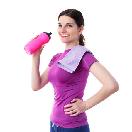 Smiling sporty woman in violet T-short with pink drinking bottle and purple towel over white isolated background, fitness, sport and lifestyle conceptの写真素材