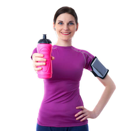 Smiling sporty woman in violet T-short with pink drinking bottle, smart phone device and headphones over white isolated background, fitness, sport and lifestyle conceptの写真素材