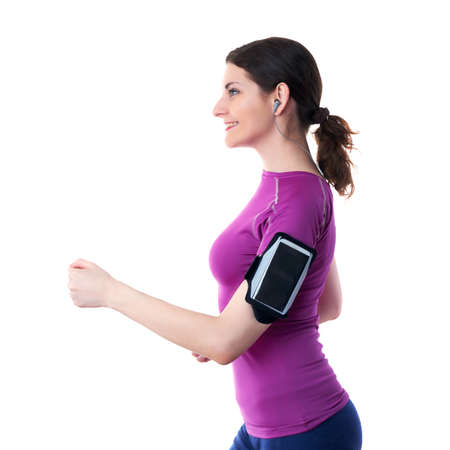 Smilling and moving, running sporty woman in violet T-short with smart phone device and headphones over white isolated background, fitness, sport and lifestyle conceptの写真素材