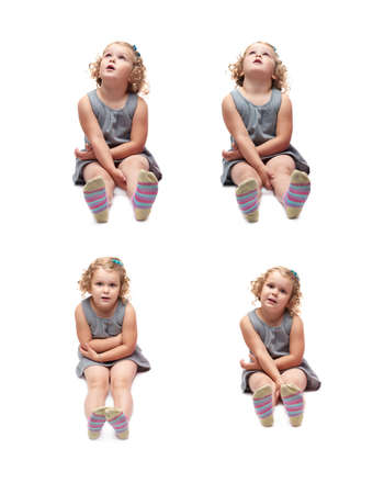 Young little girl with curly hair in gray dress sitting over isolated white backgroundの写真素材