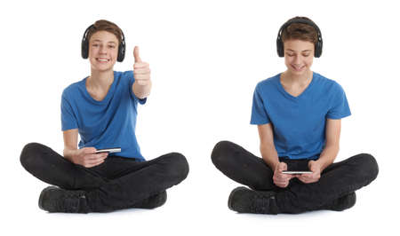 Cute teenager boy with smart phone in hands in blue T-shirt, headphones and lotus posture over white isolated backgroundの写真素材