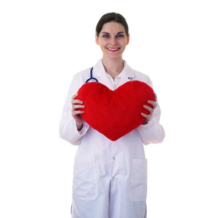 Smiling female doctor assistant in white coat over white isolated background with stethoscope and plush toy heart, healthcare, profession and medicine conceptの写真素材