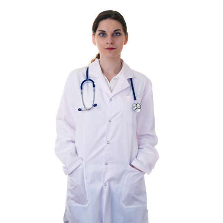 Female doctor in white coat over white isolated background with stethoscope and hands in pockets, healthcare, profession and medicine conceptの写真素材