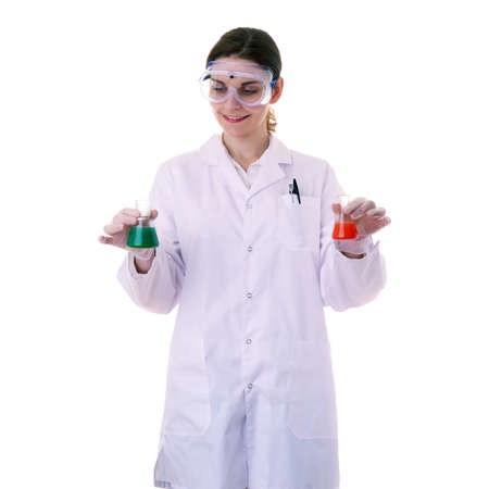 Smiling female assistant scientist in white coat and plastic protective glasses over white isolated background inspecting flask filled with substance, healthcare, profession, science and conceptの写真素材