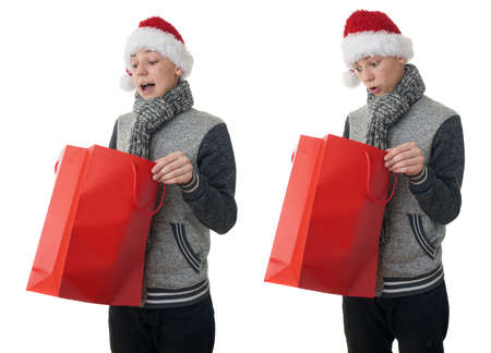 Set of cute teenager boy in gray sweater and christmas hat looking into red shopping bag over white isolated background, half bodyの写真素材