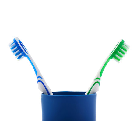 Pair of green and blue toothbrushes in blue plastic cup isolated over white background, quarrel conflict problemの写真素材