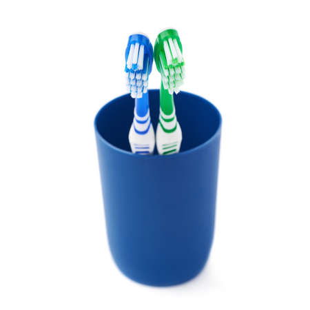 Pair of green and blue toothbrushes in blue plastic cup isolated over white background, love togetherness love conceptの写真素材