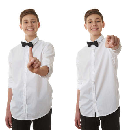 Set of cute teenager boy in white shirt and black bow tie pushing something in front himself over white isolated background, half bodyの写真素材