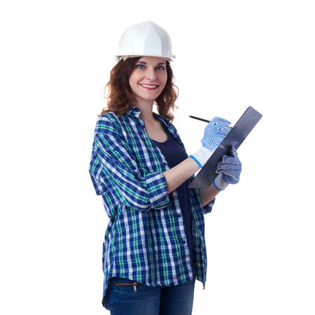 Smiling young woman in casual clothes over white isolated background in white helmet with clipboard, education, construction and architecture conceptの写真素材