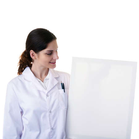 Smiling female doctor assistant scientist in white coat over white isolated background with white blank board, healthcare, profession, science and medicine conceptの写真素材