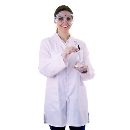 Smiling female assistant scientist in white coat and plastic protective glasses over white isolated background inspecting flask filled with substance, healthcare, profession, science and conceptの写真素材
