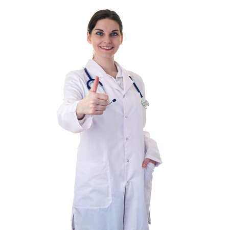 Smiling female doctor assistant in white coat over white isolated background with stethoscope and showing thumb up sign, healthcare, profession and medicine conceptの写真素材