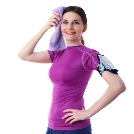 Smiling sporty woman in violet T-short with purple towel, smart phone device and headphones over white isolated background, fitness, sport and lifestyle conceptの写真素材