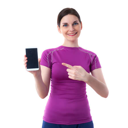Smiling sporty woman in violet T-short showing something on smart phone device over white isolated background, fitness, sport, technology and lifestyle conceptの写真素材
