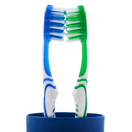 Pair of green and blue toothbrushes in blue plastic cup isolated over white background, love togetherness love conceptの写真素材