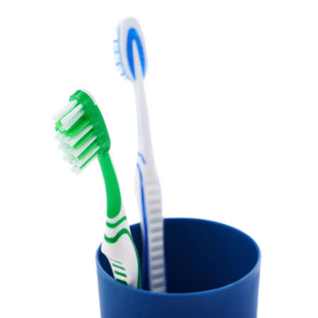 Pair of green and blue toothbrushes in blue plastic cup isolated over white background, quarrel conflict problemの写真素材