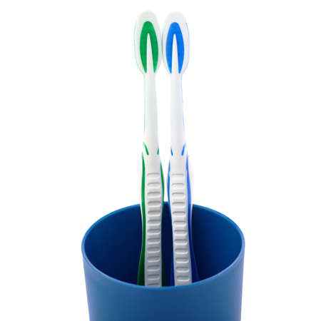 Pair of green and blue toothbrushes in blue plastic cup isolated over white background, love togetherness love conceptの写真素材
