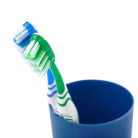 Pair of green and blue toothbrushes in blue plastic cup isolated over white background, love togetherness love conceptの写真素材