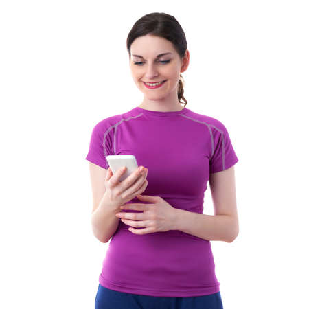 Smiling sporty woman in violet T-short using smart phone device over white isolated background, fitness, sport , technology and lifestyle conceptの写真素材