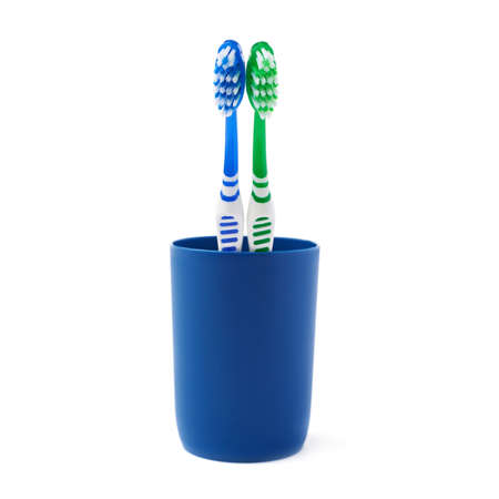 Pair of green and blue toothbrushes in blue plastic cup isolated over white background, love togetherness love conceptの写真素材