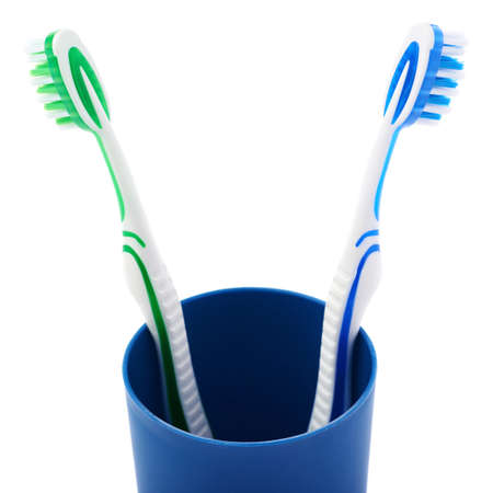 Pair of green and blue toothbrushes in blue plastic cup isolated over white background, quarrel conflict problemの写真素材