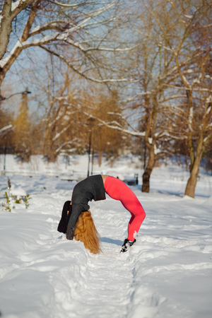 Beautiful woman doing yoga outdoors in the snow at winter timeの写真素材