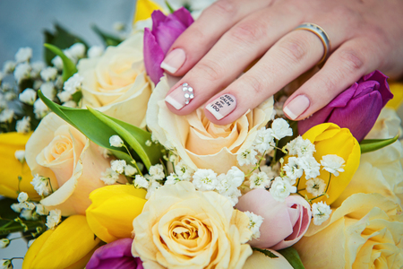 Hands with wedding rings and bouquet from rosesの写真素材