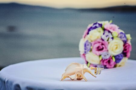 Yellow pink and purple wedding bouquet from roses. Beach and sea backgroundの写真素材