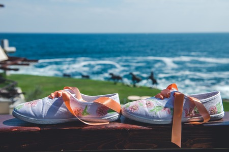 Beach Wedding Details in front of the sea. Bridal floral sneakers.の写真素材