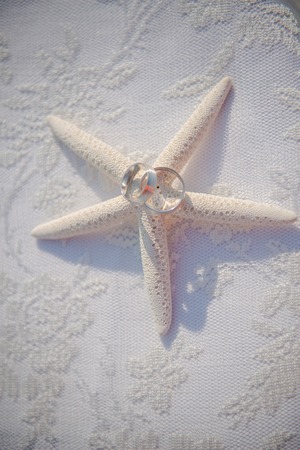 Wedding glasses and rings on the shells and starfish. Table with lace cover. Close up viewの写真素材