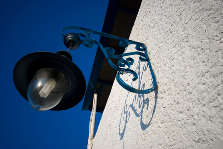 closeup of a street lamp and white wall under a blue sky in Greeceのeditorial素材