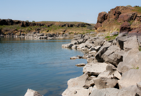 Rocky desert lake shore with grass and white & red rocksの写真素材