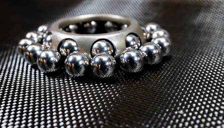 Loose ball bearings surrounding an automotive wheel bearing on carbon fiber cloth.の写真素材
