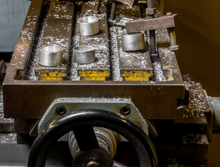 Vintage antique automotive machine shop milling table with aluminum machined components and filings with an adjustment wheelの写真素材