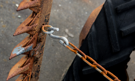 Vintage antique automotive tractor wheel and cutter implement and chain showing rust and ageの写真素材