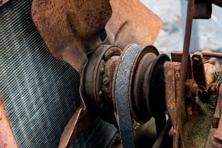 Vintage antique automotive tractor rusty fan blade and belt behind the radiator with pulleys showing