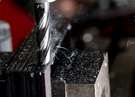 Bridgeport CNC end mill finishing a stack of steel plate with metal filings chips and light smoke...