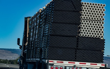 Semi tractor trailer hauling pvc pipe conduit with a shadowの写真素材