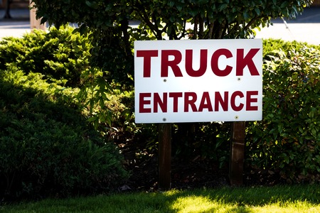 Truck entrance sign on green grass with trees and bushes in the backgroundの写真素材