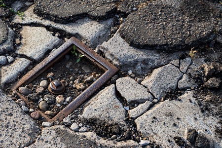 Cracked broken distressed pavement with broken utility hook up that is rustyの写真素材