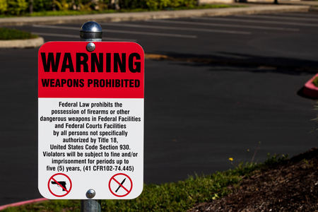 Warning weapons prohibited sign in front of a parking lot in daylightの写真素材