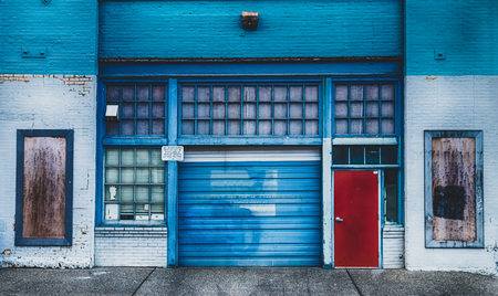 Antique old garage mechanic shop storefront with doors and windowsの写真素材