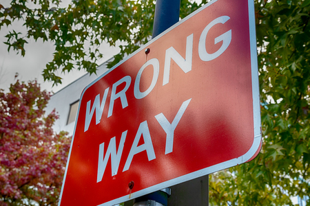 Red wrong way sign on a post with treesの写真素材