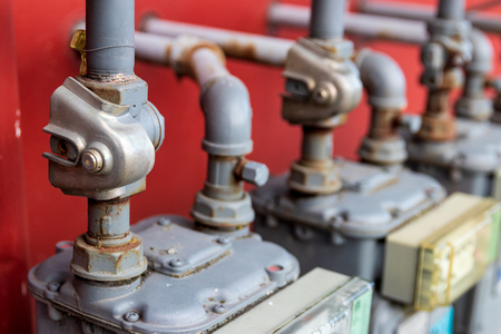 Abstract building power and gas meters with pipes going in a red wallの写真素材